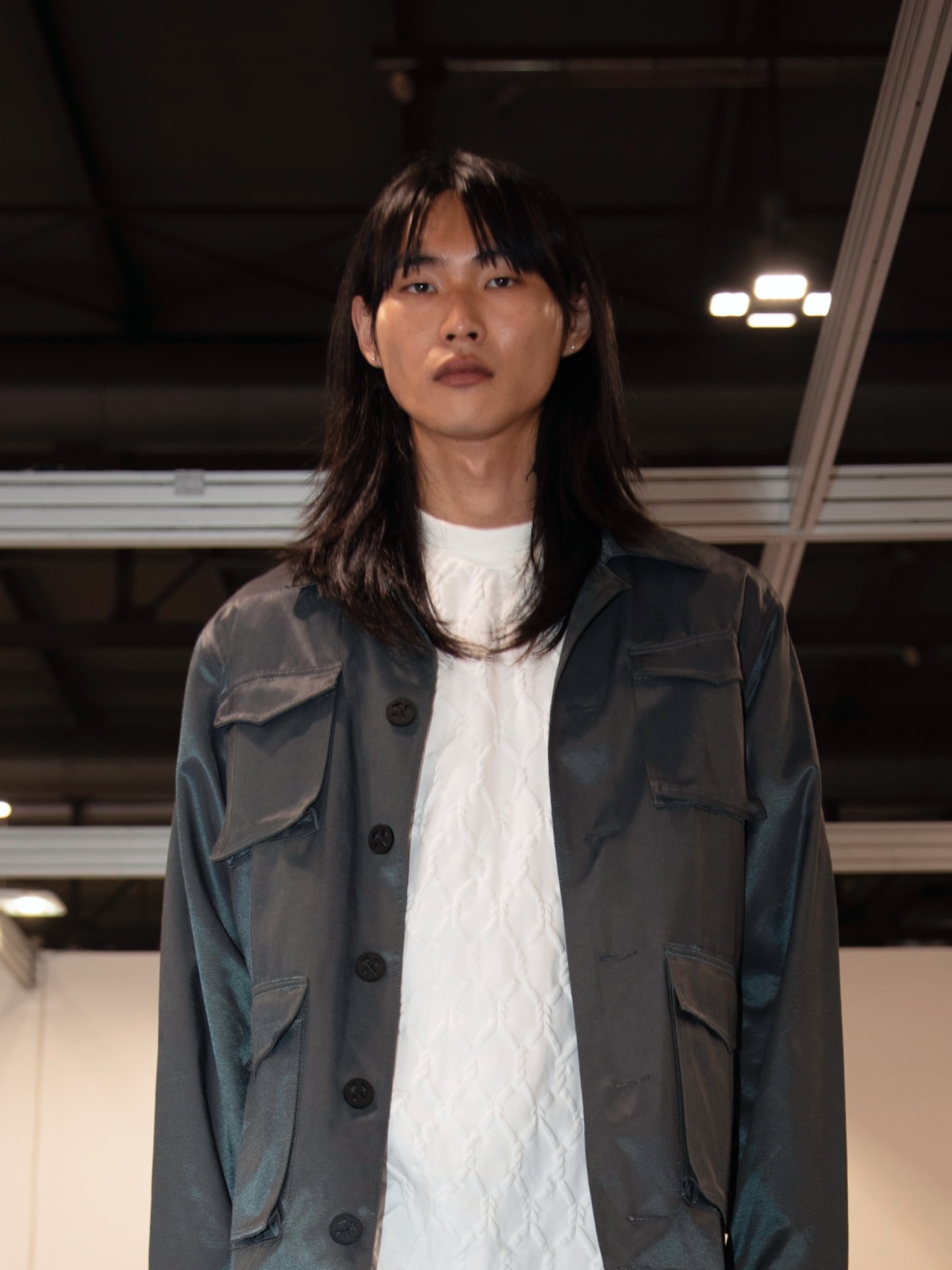 Model wearing a gray oversized jacket from the KOVARI collection at the International Mittelmoda Lab in Milan