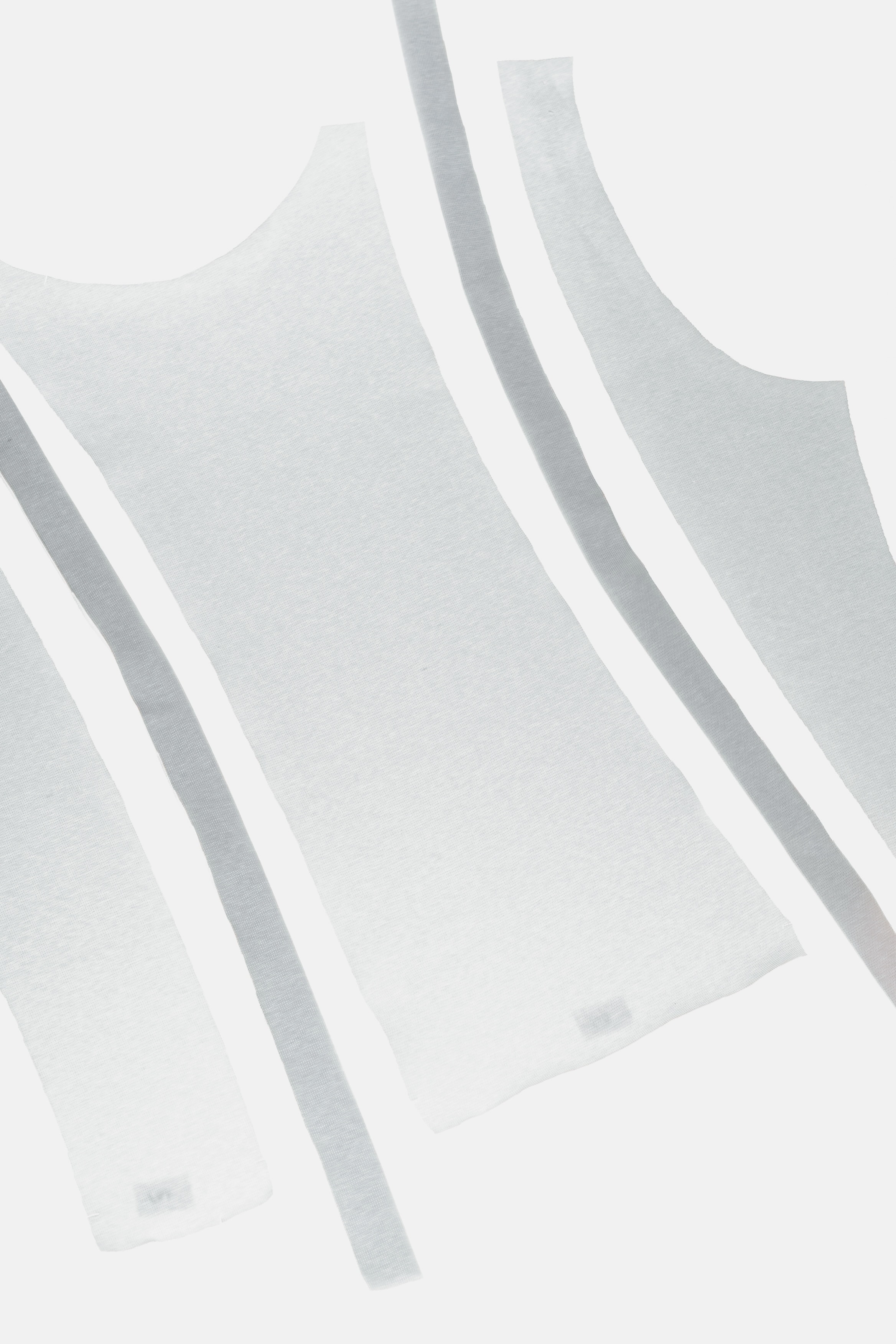 Close-up detail of knitted tank top pattern pieces showing tape finishing along the edges.