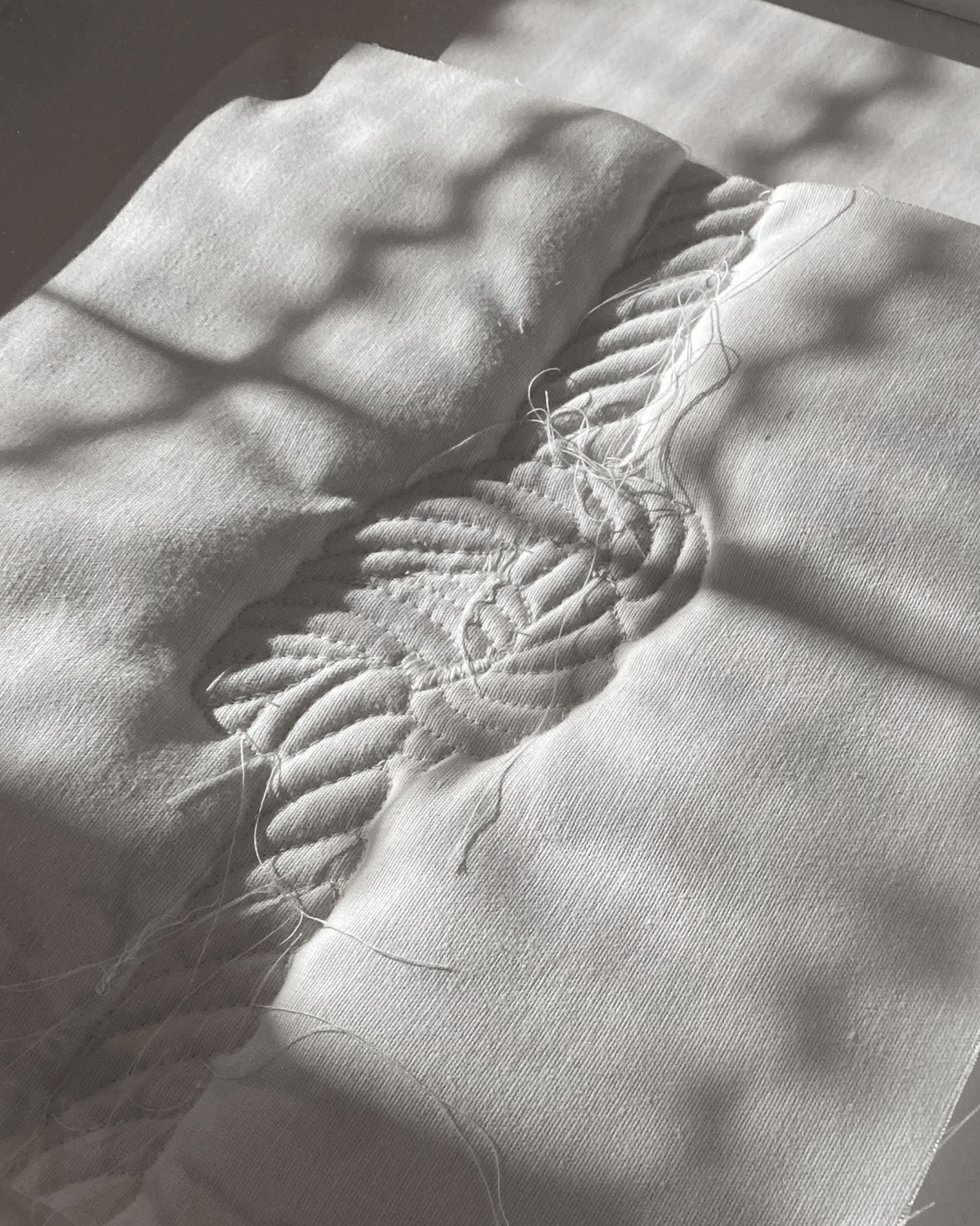 Detail photo of textile artwork made of padding, canvas, and thread.